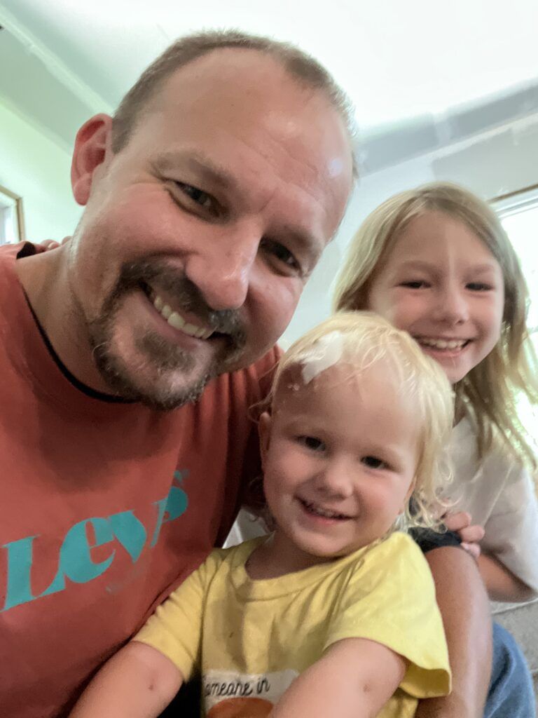 Isla smiling with her Dad and sister at the hospital.