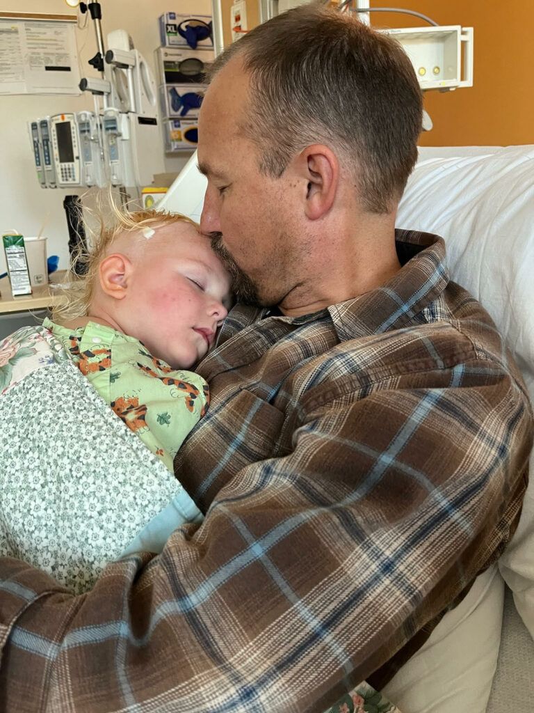 Isla sleeping on her Dad in the hospital bed.