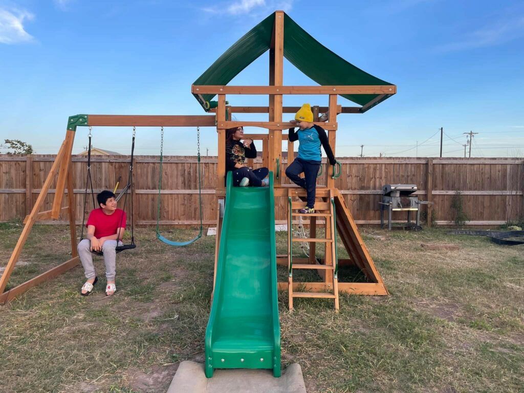 Jose, age 4, and his siblings Monique, age 15, and Rafael, age 13, on their new playset.