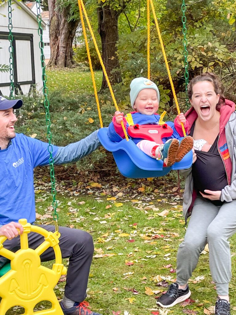 Remi swinging while her mama and papa bears grin from ear to ear