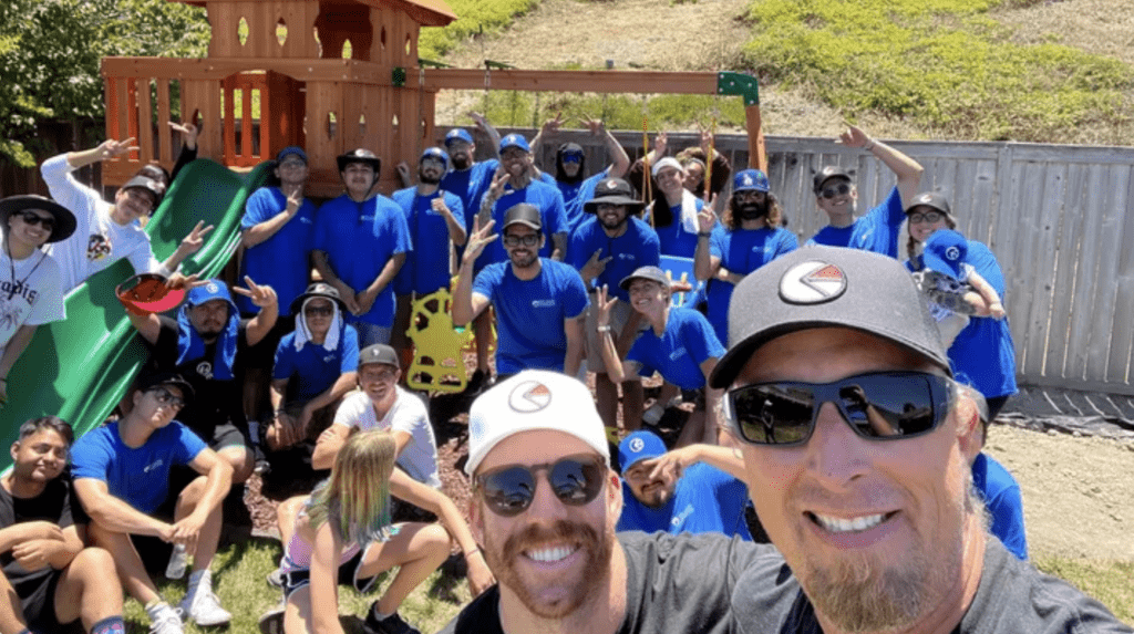 Roc Solid volunteers pose in front of a playset they built together for a family fighting childhood cancer.