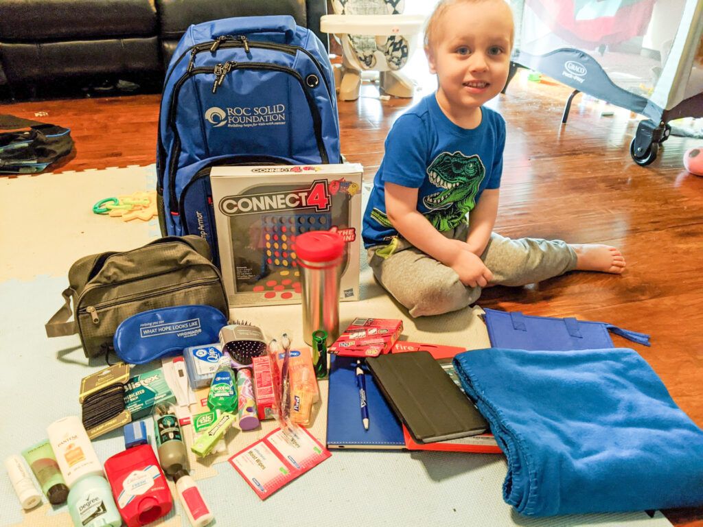Jacob with his Roc Solid Ready bag that has essential hospital supplies such as toiletries, a table, a phone charger, games, a blanket, a journal and more!